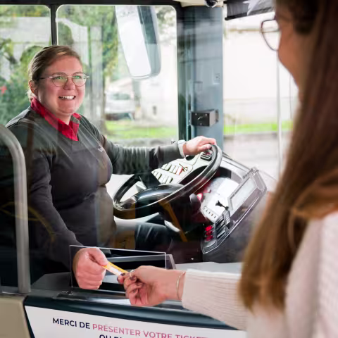 Conductrice de bus Soléa donnant un ticket à un client montant à bord